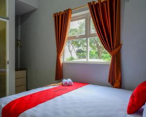 a bedroom with a red and white bed with a window at RedDoorz @ City Park Medoho Semarang in Alastuwo