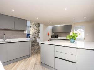 a kitchen with white cabinets and a vase of plants at Drovers Barn in Corwen