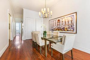 a dining room with a glass table and white chairs at City View Condo with Private Rooftop in New Orleans