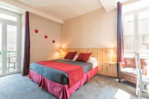 a bedroom with a bed and a chair and windows at Auberge Le Cabaliros in Argelès-Gazost