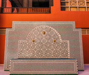 a white bench sitting in front of an orange wall at Diwane Hotel & Spa Marrakech in Marrakesh