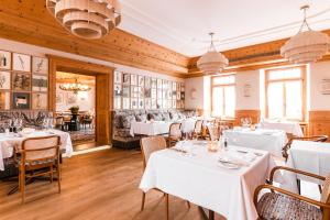 un comedor con mesas y sillas blancas en Hotel Steinbock Pontresina en Pontresina