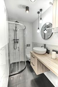 y baño con ducha acristalada y lavamanos. en Apartament Akademia, en Legnica