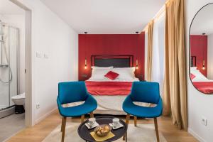 a hotel room with a bed and two blue chairs at Sweet Nest Korzo in Rijeka
