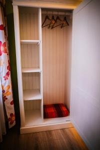 a small closet with white shelves and a red blanket at Brassai Square in Braşov