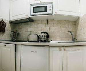 a kitchen with white cabinets and a microwave at Brassai Square in Braşov