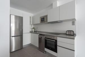 a kitchen with white cabinets and a stainless steel refrigerator at Royal Flats in Las Palmas de Gran Canaria