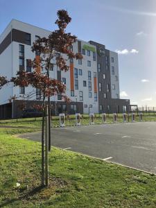 un árbol en el césped frente a un edificio en B&B HOTEL Les Herbiers, en Les Herbiers