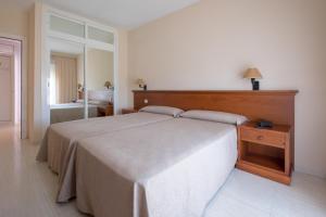 a bedroom with a large bed with a wooden headboard at Aparthotel las Dunas in Chiclana de la Frontera +65 photos