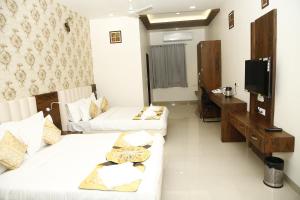 Sala de estar con 2 camas y TV en Hotel Manas Plus, en Khandwa