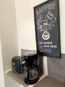 a coffee maker next to a coffee pot and a sign at City Apartment Bremerhaven in Bremerhaven