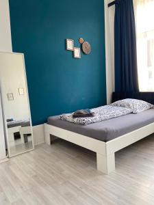 a bedroom with a bed with a blue wall and a mirror at City Apartment Bremerhaven in Bremerhaven