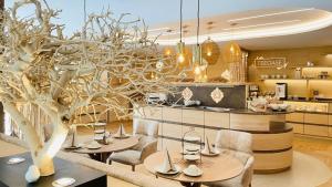 a dining room with tables and chairs and a tree at Fichtenwald-Ihr Boutique I Glück`s Hotel - Ihr Kraftort - Wasserwelten Bad Füssing in Bad Füssing