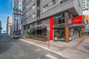 a building with a red sign on the side of a street at Hotel Melo in Balneário Camboriú