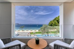 a room with a large window with a view of the ocean at Vathi Cove Luxury Resort & Spa in Chrysi Ammoudia