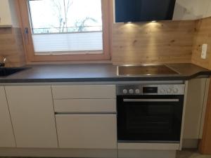 een keuken met witte kasten en een zwarte oven bij Haus Grünbacher in Lienz