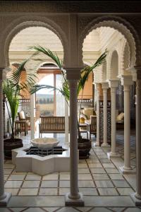 Sala de estar con columnas, mesa y sillas en Alborada Riad, en Puebla de Almenara