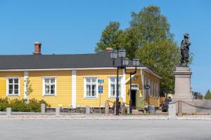 a yellow building with a statue in front of it at Boutique Hotel Langin Kauppahuone in Raahe