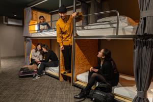 grupa osób siedzących na łóżkach piętrowych w obiekcie Wise Owl Hostels River Tokyo w Tokio