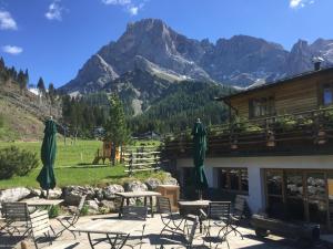 eine Terrasse mit Tischen und Stühlen mit Bergen im Hintergrund in der Unterkunft Chalet Prà delle Nasse in San Martino di Castrozza