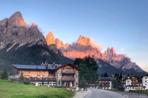a house in a village with mountains in the background at Chalet Prà delle Nasse in San Martino di Castrozza