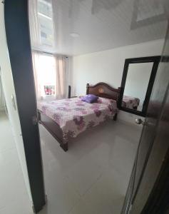 Dormitorio pequeño con cama y espejo en Linda y acogedora casa, en Pereira