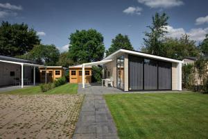 a house with a lawn in front of it at Recreatiepark Jachthaven De Veerstal Lathum - Luxe Chalet in Lathum
