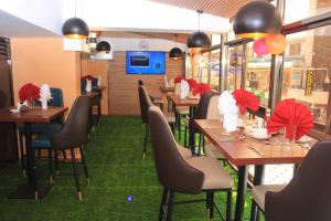 un ristorante con tavoli e sedie in legno con ombrelloni rossi di Vickmark Hotel a Nakuru