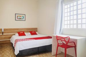 a bedroom with a bed and a red chair at OYO Hotel Brisa Tropical, Brasília in Brasília