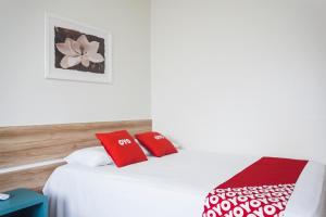 1 dormitorio con 1 cama con almohadas rojas y blancas en OYO Hotel Brisa Tropical, Brasília, en Brasilia