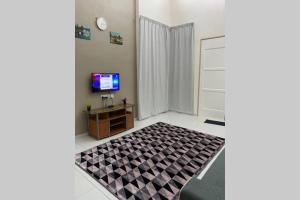 een woonkamer met een televisie en een tapijt bij Twilight Imani Homestay Changlun in Changlun
