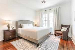 um quarto branco com uma cama e uma cadeira em Stunning 5 BR Urban Oasis Downtown NOLA em Nova Orleans