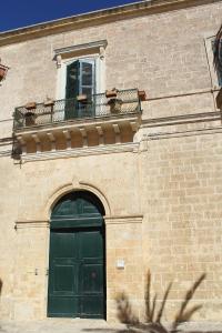 ガリアーノ・デル・カーポにあるPalazzo Bitontiの緑のドアとバルコニー付きの建物