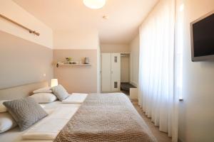 a bedroom with a large white bed and a television at Gästehaus am Wasserschloss & Restaurant Wasserschloss Inzlingen in Inzlingen