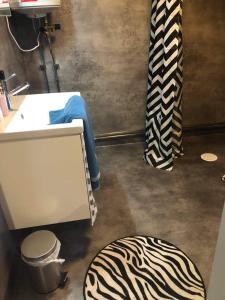 a person sitting in a bathroom with a sink and a zebra rug at Strandnära Stuga Vänersnäs in Vargön