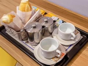 una bandeja con tazas y platillos en una mesa en OYO Hotel Brisa Tropical, Brasília, en Brasilia