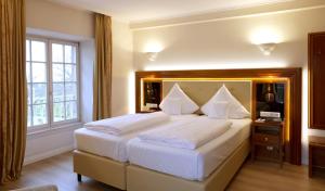 1 dormitorio con 1 cama grande con sábanas y almohadas blancas en Hotel Schloss Edesheim en Edesheim
