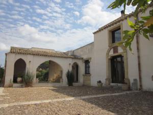 a white building with an archway in a yard at Casale Alma in Marsala