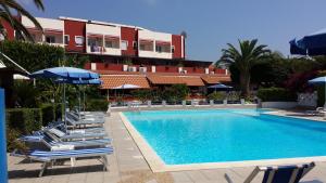 a swimming pool with chairs and umbrellas next to a building at Residenza Felix in Capo Vaticano