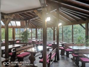 a restaurant with wooden tables and benches and windows at Ribkata Family Hotel in Smolyan
