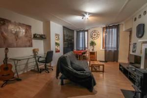 ein Wohnzimmer mit einem Sofa, einem Tisch und einer Gitarre in der Unterkunft Calm studio in the historical centre - Dodo et Tartine in Guillestre