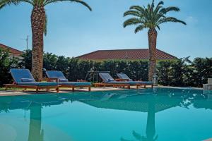 a swimming pool with two palm trees and lounge chairs at Amor Villa in Laganas