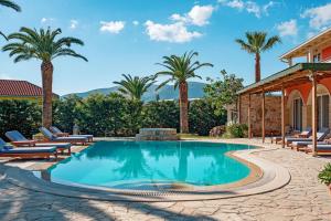 a swimming pool with lounge chairs and palm trees at Amor Villa in Laganas