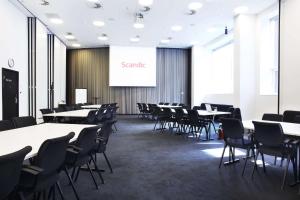 una sala de conferencias con mesas, sillas y una pantalla en Scandic Aarhus City, en Aarhus