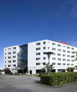 a large white building with a red sign on it at Scandic Aarhus Vest in Aarhus