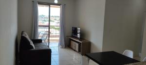 a living room with a couch and a television and a table at Apto a 3 minutos do Thermas!! in Olímpia