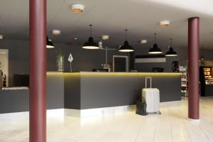 a lobby with a counter with a suitcase and pendant lights at Scandic Silkeborg in Silkeborg