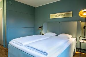 a bedroom with a white bed with a blue wall at Scandic Silkeborg in Silkeborg