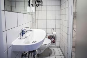 a white bathroom with a sink and a toilet at Scandic The Mayor in Aarhus