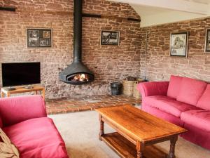 a living room with two pink couches and a fireplace at Stockbatch Granary in Shrewsbury